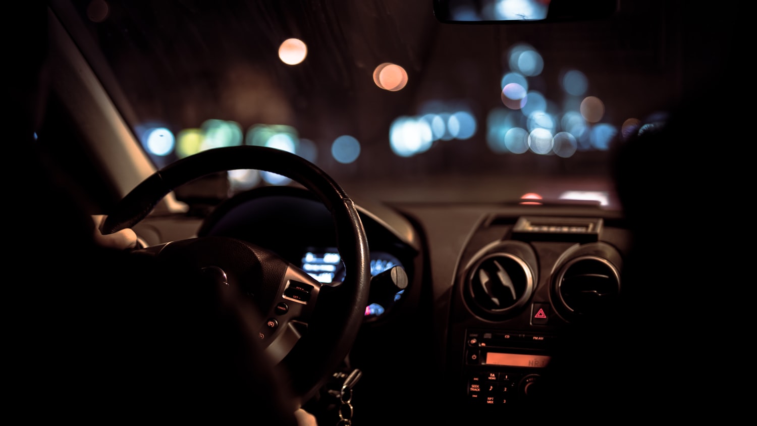 Hands on the wheel at night, city lights ahead