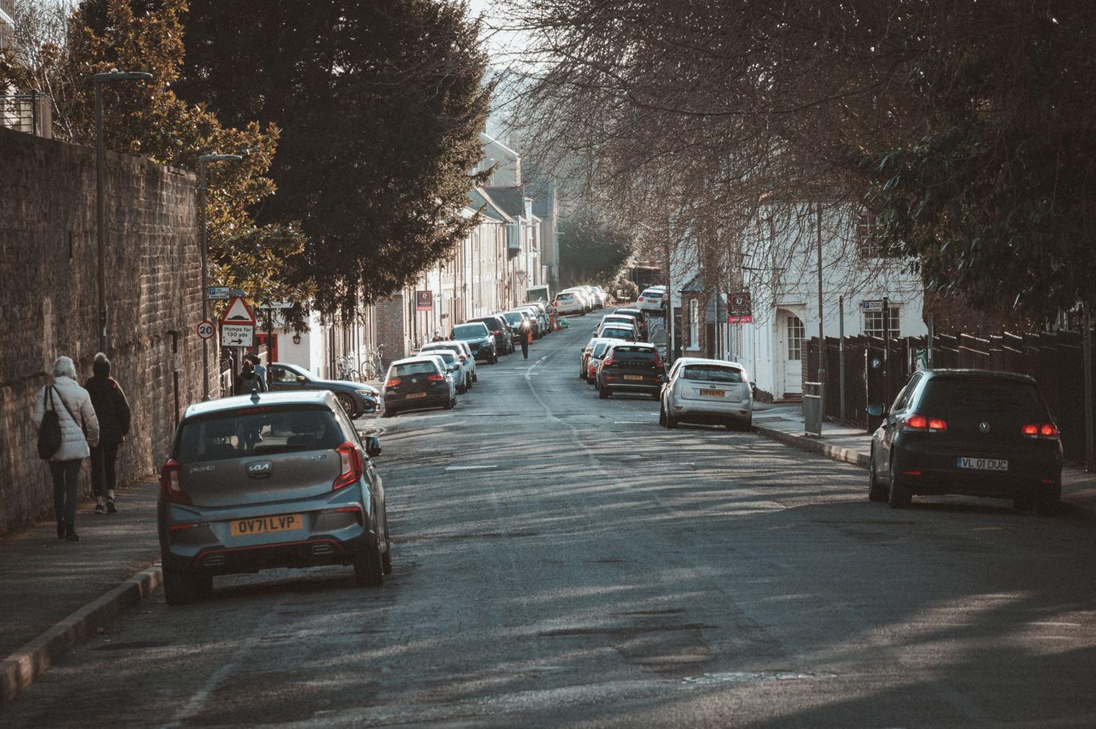 A small hatchback parked on a sunlit British street as its owner walks to the shops