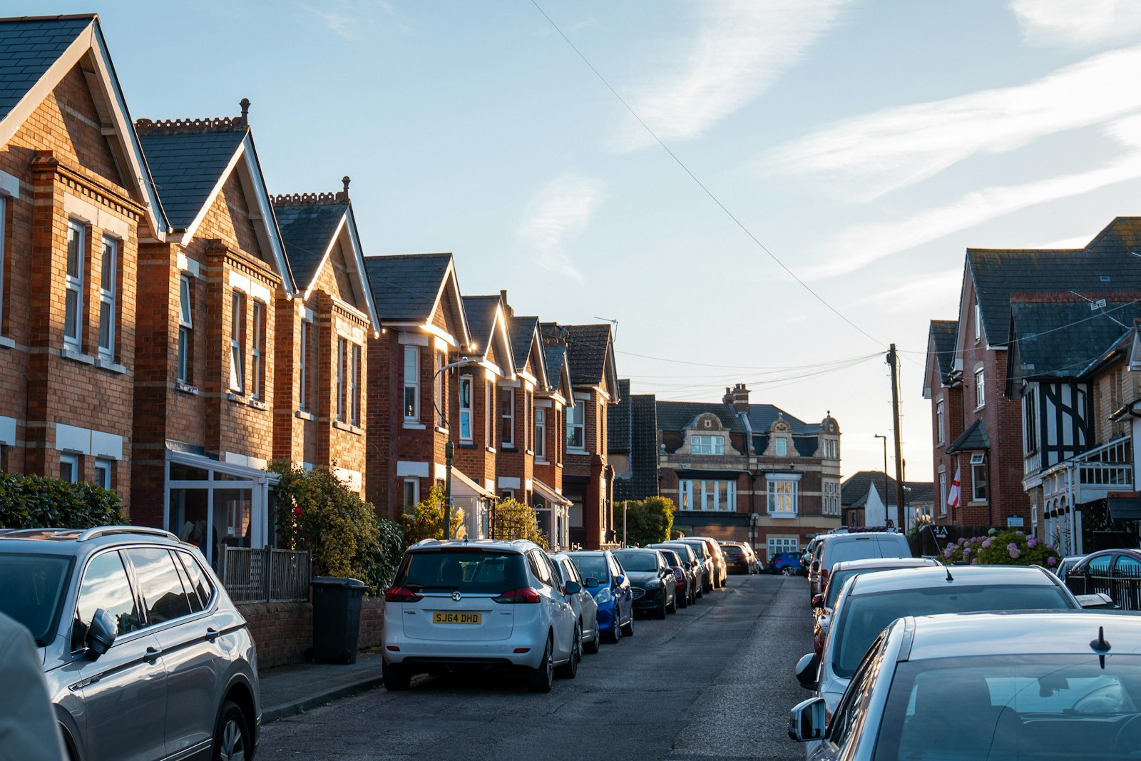 Cars parked safely outside a row of British houses in the morning sun
