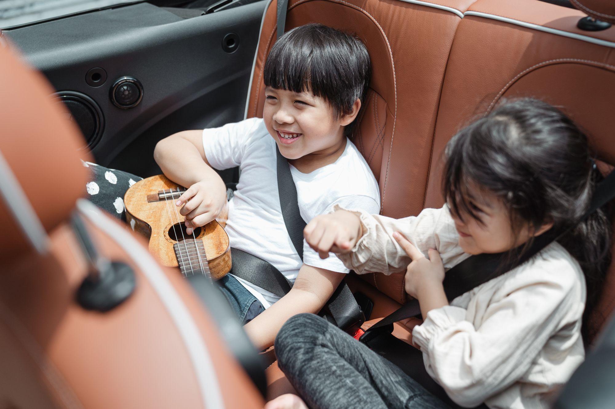 Two children laughing together, safely belted in the back seat of the family car