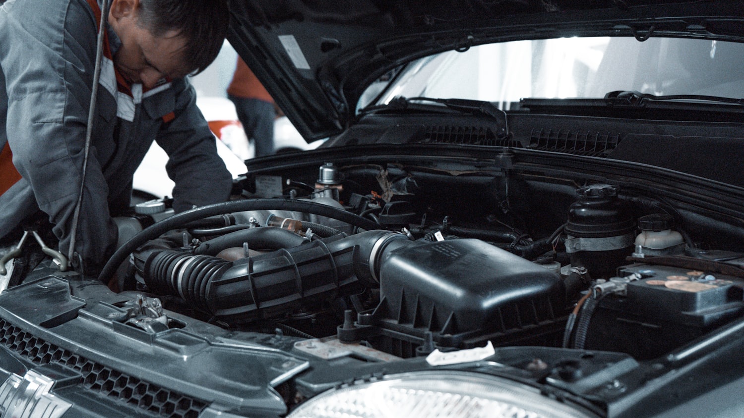 A technician working in a vehicle engine bay
