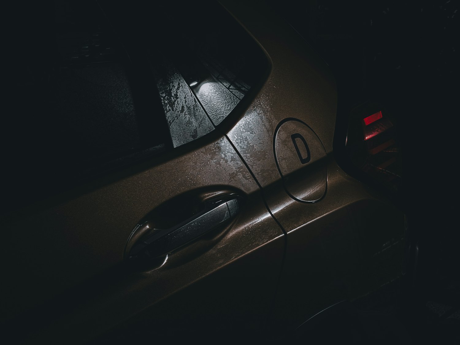 A car door handle at night, lit low and tense — the moment before a break-in