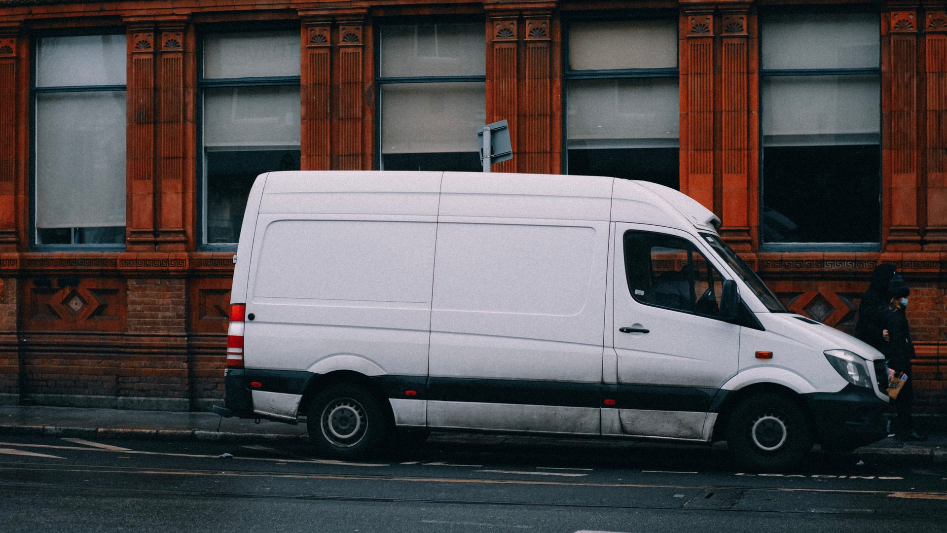 A tradesperson's work van parked on a city street, side profile