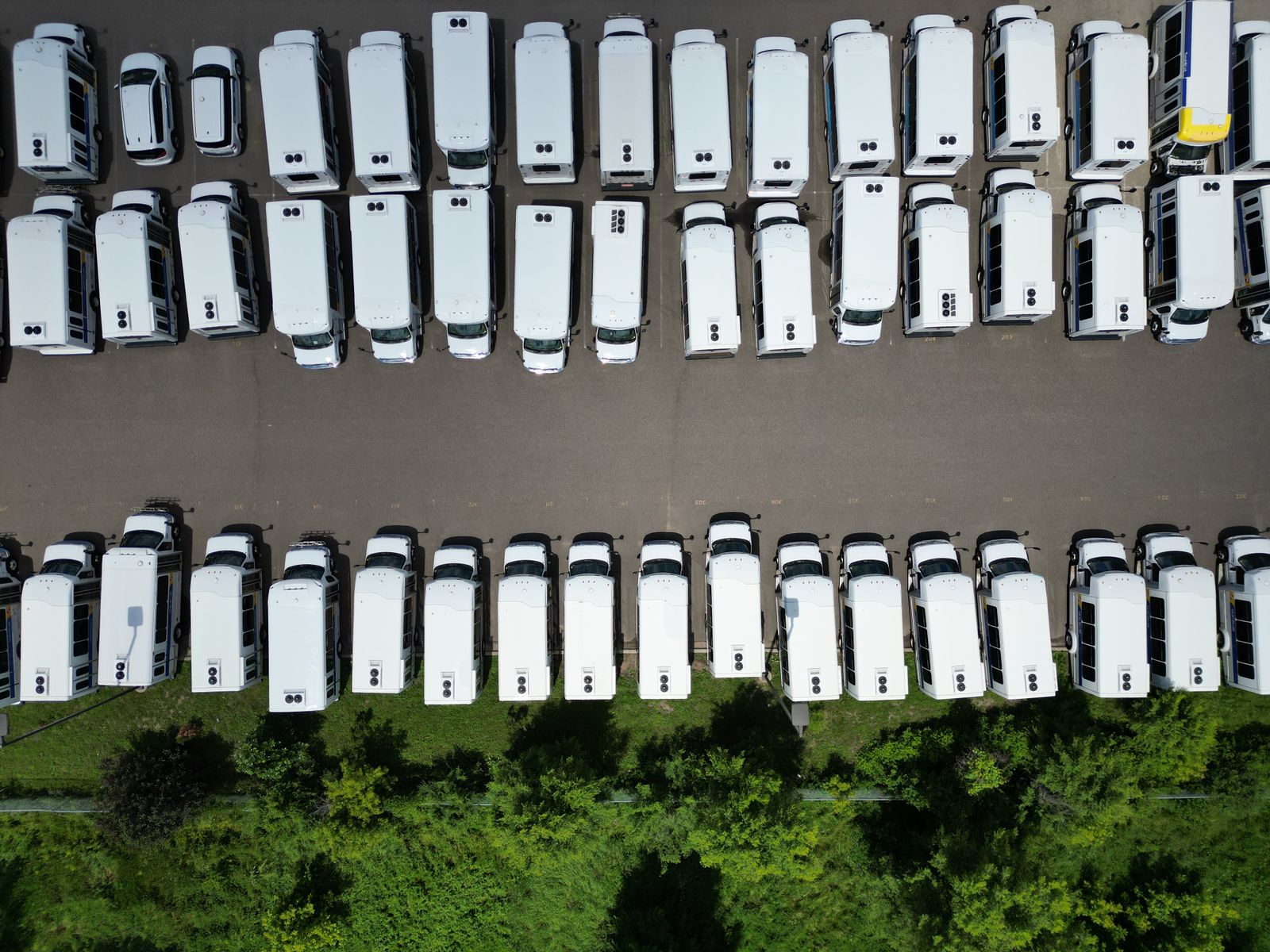 Rows of white work vans parked together in a yard, seen from above