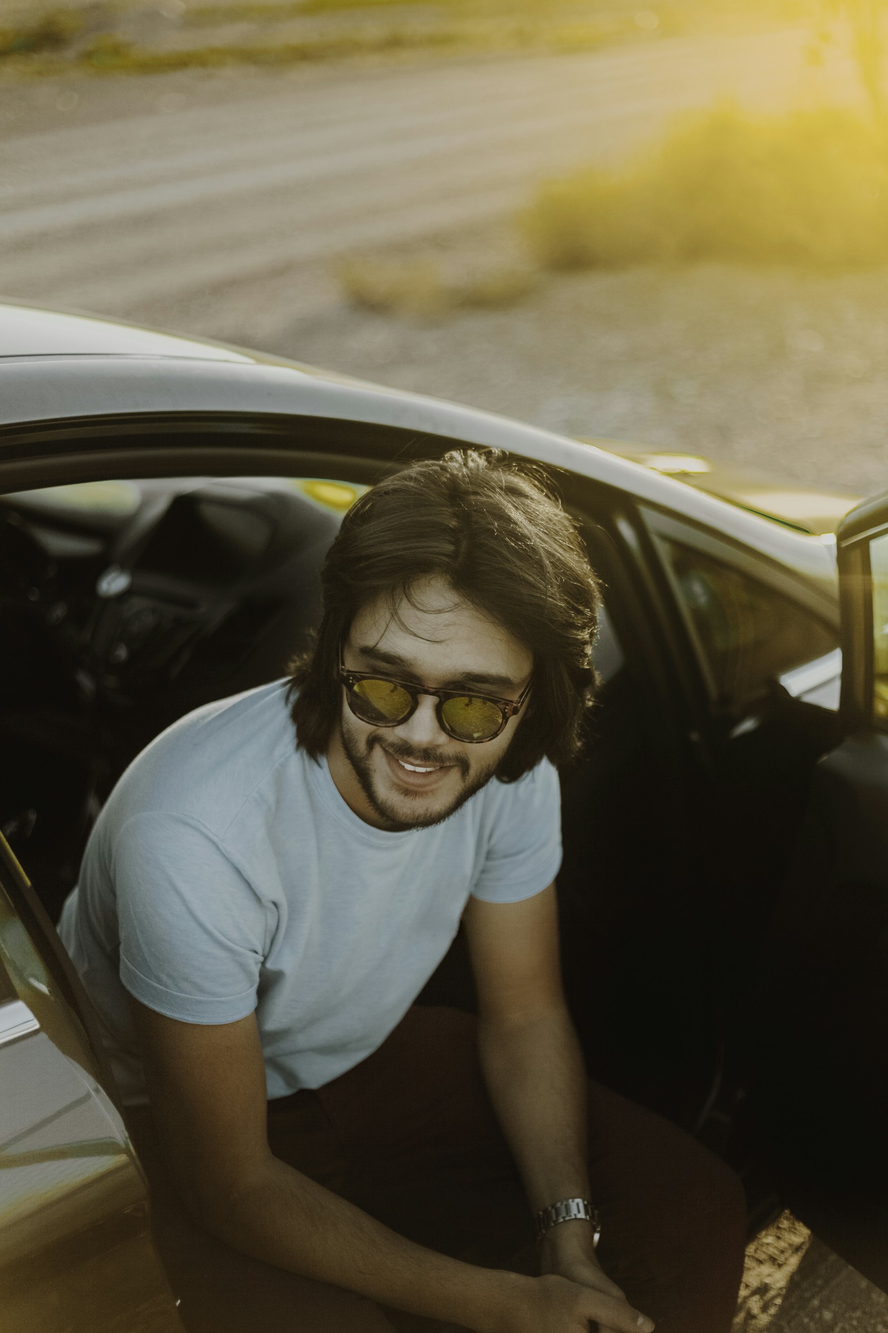 A young driver standing beside their first car