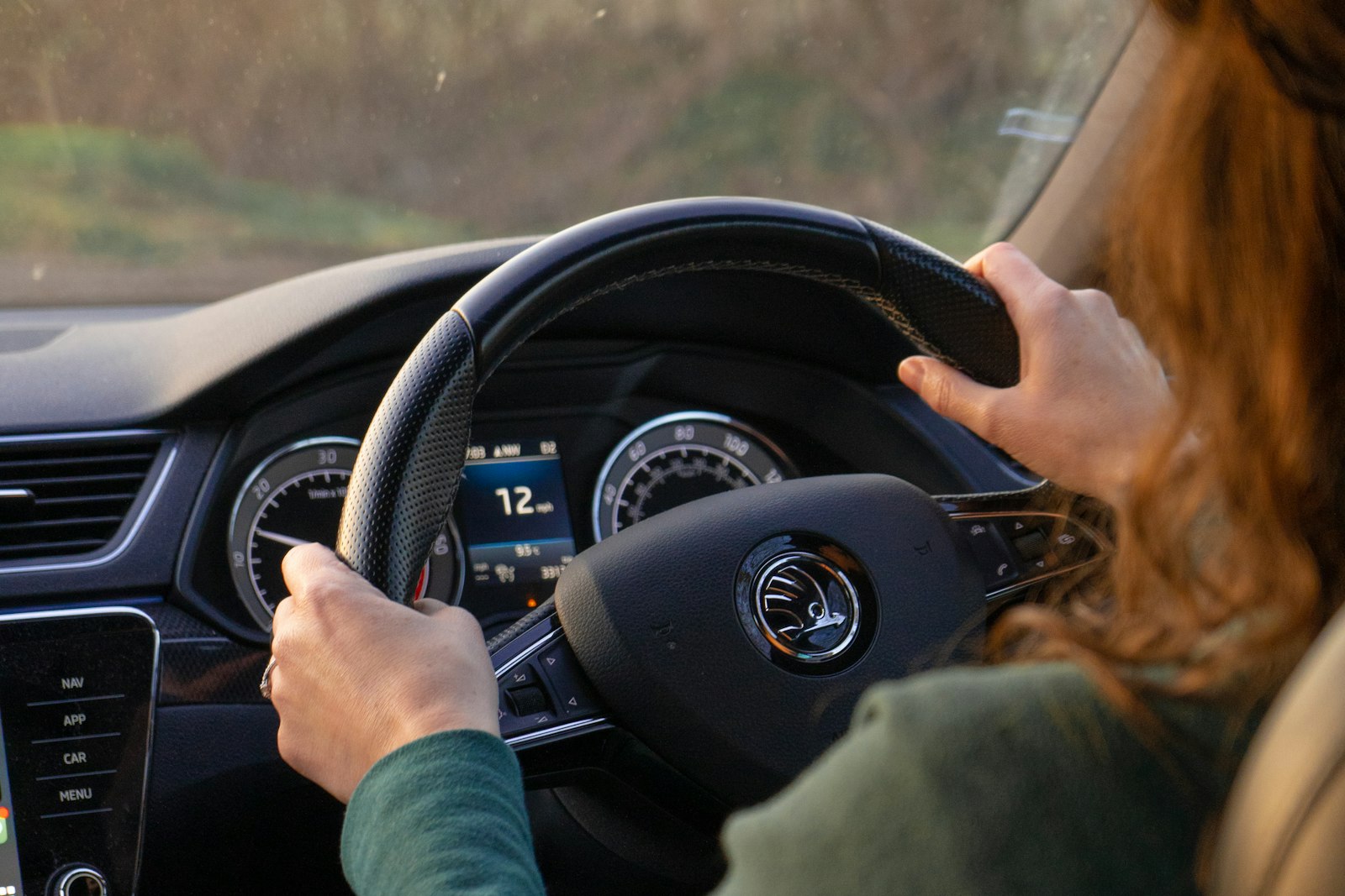 A young woman's hands on the wheel of her right-hand-drive car as she pulls away